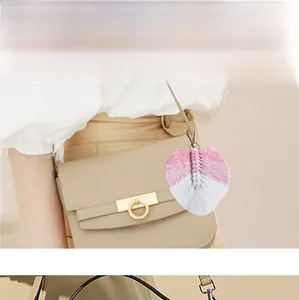 Dettaglio di un portachiavi a foglia macramè rosa e bianco su una borsa beige