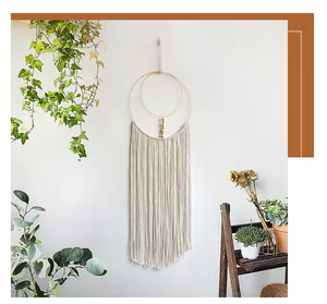 Close-up of bohemian wall hanging with golden metal rings and long off-white cotton tassels
