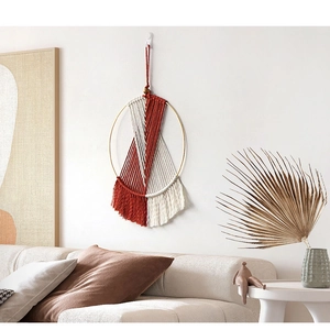 Detail of handmade macramé wall hanging with reddish-brown tassels on a gold metal ring