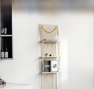 Detail of hand-woven macrame wall shelf featuring three wooden tiers and elegant boho fringe