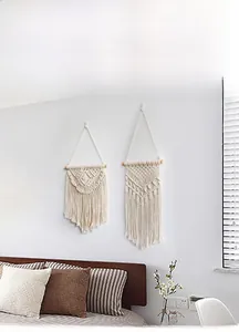 Detailed close-up of handmade bohemian woven wall hanging with cotton tassels and wood bar