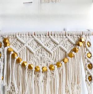 Close-up of high quality gold beads and hand-woven macrame detail on boho wall hanging