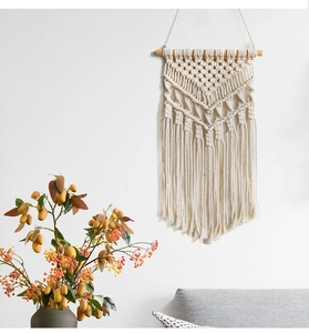 Close-up of bohemian hand-woven cotton macrame wall hanging with wooden rod and fringe
