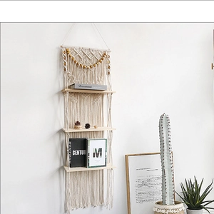 Detail view of the handmade woven cotton ropes and wooden shelves of the boho wall hanging