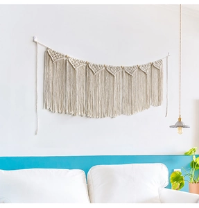Detail of bohemian hand-woven tapestry with triangular patterns and long cotton tassels