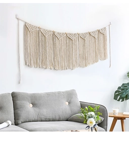 Detail of bohemian macrame wall hanging with triangle weaves and fringe on white wall