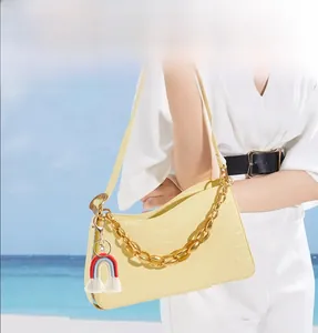 Dettaglio portachiavi arcobaleno con frange su borsa a mano gialla effetto coccodrillo