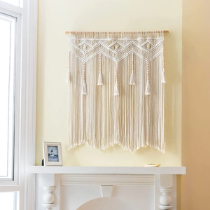 Detail of bohemian macrame wall hanging with geometric weave, long tassels and wooden beads