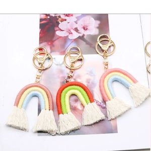 Dettaglio di tre portachiavi arcobaleno fatti a mano con corda di cotone e nappine bianche