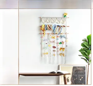 Detail view of woven cotton rope hair accessory organizer with wooden rods and boho tassels