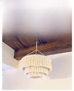 Detail of three-tier handcrafted macrame lamp shade with woven cotton tassels in beige