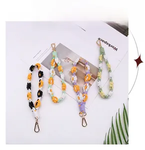 Macro detail of handmade woven flower wrist straps with gold metal lobster clasps