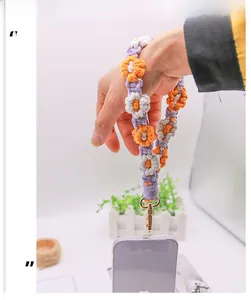 Close-up of handmade woven flower phone strap with purple and orange patterns and gold clasp