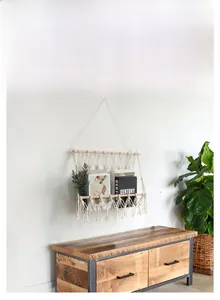 Detail of bohemian hand-woven cotton macrame tapestry with wooden magazine storage shelf