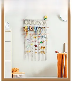 Detail of Nordic woven cotton hair clip organizer with fringe and wooden rods
