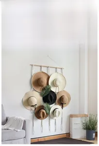 Detail of hand-woven macrame hat rack organizer with wood bar on white wall