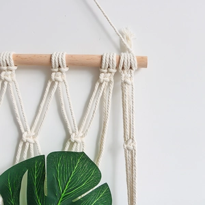 Handwoven macrame wall hanging magazine rack made of natural beige cotton rope and wood