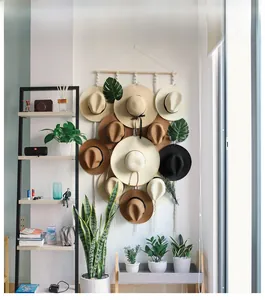 Detail view of handmade macrame hat holder with wooden bar and multiple woven hats on the wall