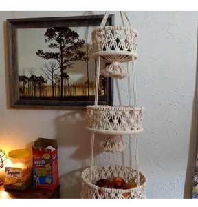 Detailed close-up of handmade three-tier bohemian cotton rope hanging fruit basket with tassels