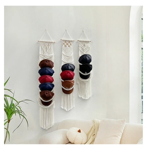 Dettaglio del portacappelli boho in cotone intrecciato con asta in legno e vani a livelli
