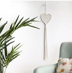 Close-up of handmade woven heart macrame wall hanging with long cotton tassels