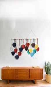 Détail de décoration murale en macramé avec feuilles colorées et support en bois naturel