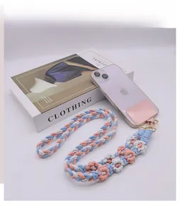 Dettaglio del cordino floreale per telefono tessuto a mano con fiori di cotone rosa e blu e gancio