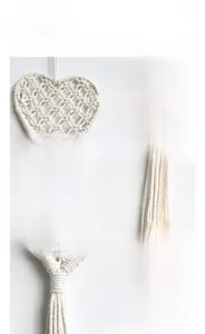 Detailed macro view of handmade woven cotton heart tapestry with bohemian fringe design