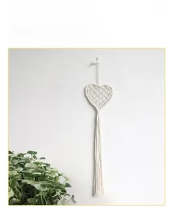 Detail of bohemian handmade woven cotton heart tapestry with long elegant tassels