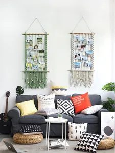 Detail of hand-woven macrame photo display with wooden clips in green and white tones