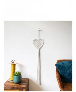 Detailed Bohemian style handmade woven heart tapestry with long cotton tassels on a white wall
