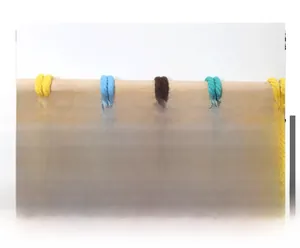 Détail de cordes en coton tissé coloré suspendues à une barre en bois naturel rond