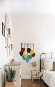 Détail de la tenture murale en feuilles tissées colorées avec mât en bois naturel et macramé