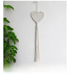 Close-up of cream handmade macrame heart wall hanging with elegant cotton fringe detail