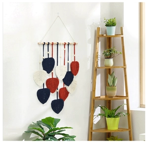 Détail d'une tenture murale nordique avec des feuilles en macramé colorées et bois naturel