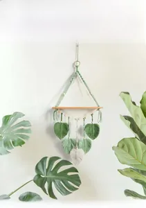 Detail of bohemian woven tapestry shelf with handmade macrame leaf patterns and wood bar