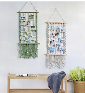Detail of bohemian hand-woven macrame photo display with wooden clips and fringe