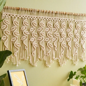 Detail of bohemian macrame wall hanging with handmade wave patterns on a wooden rod