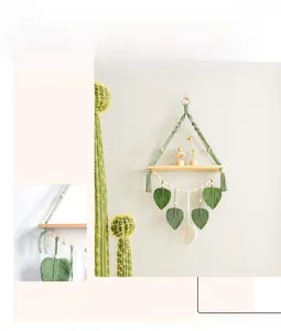 Detail of handmade bohemian wall shelf with macrame leaf tassels and wooden plant stand
