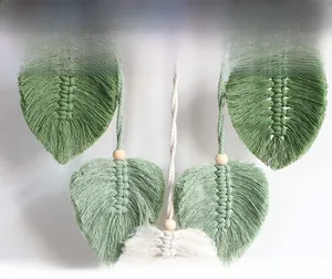 Detail of handmade macrame leaf tassels in forest green and beige cotton with wood beads