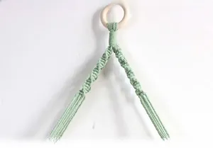 Detail of hand-woven light green cotton rope spiral knotting with a natural wood ring