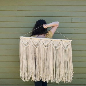 Handmade bohemian macrame wall hanging with fringes and wooden rod for home decor