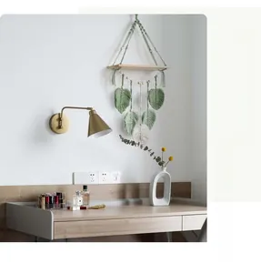Detail of macramé wall shelf with green woven leaves and natural wood shelf