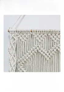 Detailed close-up of handmade macrame wall hanging with cotton rope and fringe textures