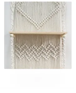 Detail of bohemian hand-woven cotton macrame wall shelf with natural wooden board