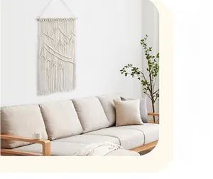 Detail eines handgefertigten Boho-Wandteppichs mit gewebter Berglandschaft an einer weißen Wand