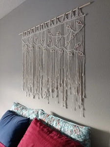 Detail of bohemian macrame wall hanging featuring handwoven leaf patterns and wooden beads