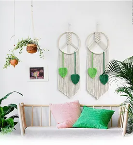 Detailed close-up of macrame wall hanging with wooden ring and green leaf tassels