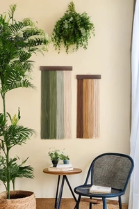 Detail of two boho woven macramé wall hangings with green and brown gradient tassels