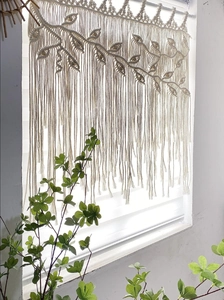 Close-up of handmade bohemian woven tapestry featuring leaf patterns and wooden beads
